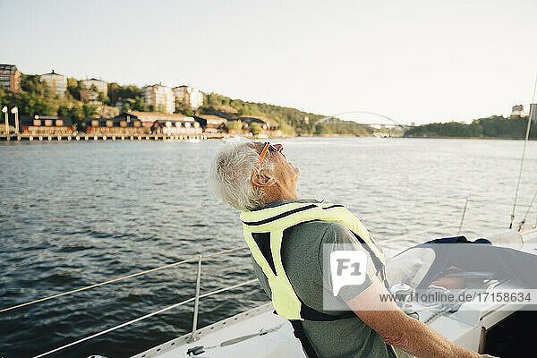 Senior Mann lachend im Boot gegen den Himmel am sonnigen Tag