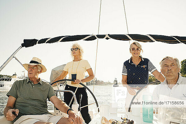 Happy senior couples sailing in boat on sunny day