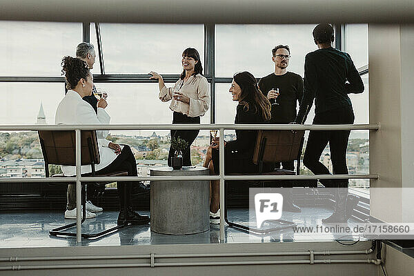 Lächelnde männliche und weibliche Kollegen trinken Wein beim Feiern in Büro Party