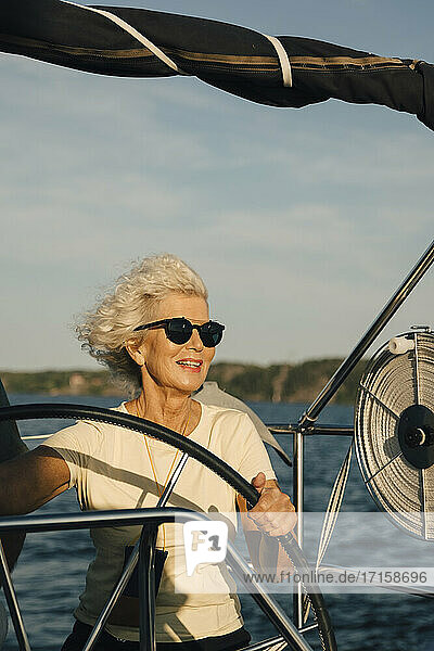 Lächelnde ältere Frau Segelboot im Meer an einem sonnigen Tag
