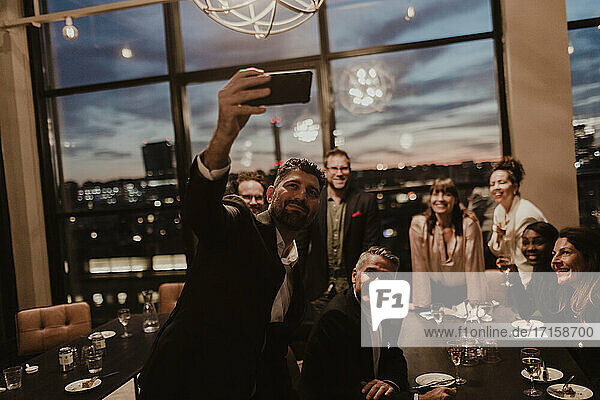 Lächelnde Geschäftsleute nehmen Selfie auf Handy im Büro während der Party