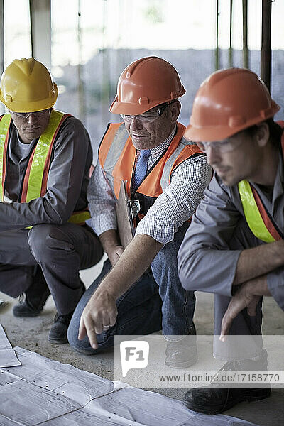 Male architect explaining plans to construction workers on site