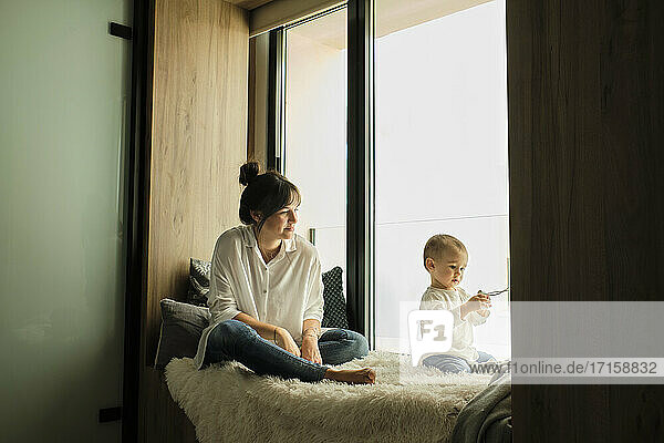 Mutter sitzt mit ihrer kleinen Tochter am Fenster