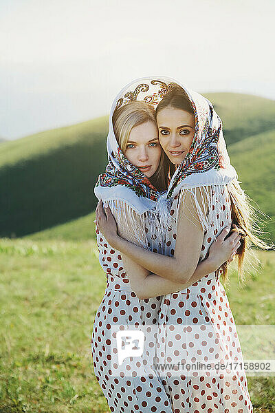 Lesbian couple with headscarf embracing each other while standing on meadow