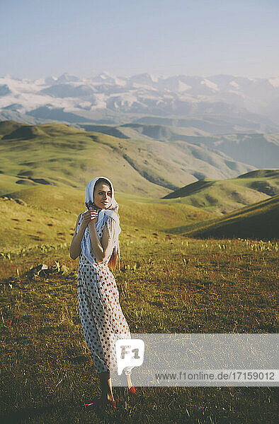 Young woman with polka dot dress standing against mountains