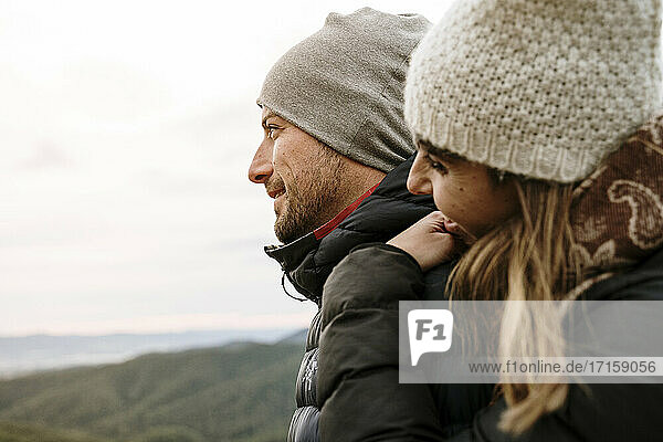 Smiling couple in warm clothing looking away during winter