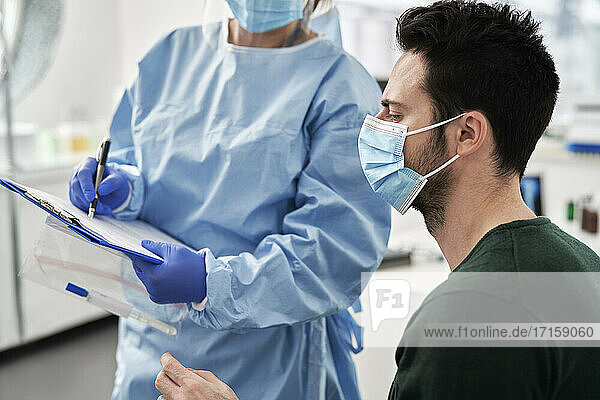 Female medical professional explaining procedures to male patient before collecting sample at clinic