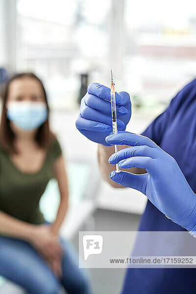 Male medical professional checking syringe with COVID-19 vaccine