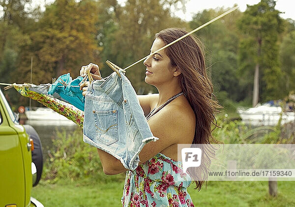 Young woman hanging out washing clothes on clothesline by camper van