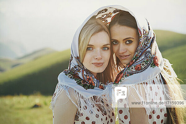 Beautiful lesbian couple with polka dot dress sharing headscarf during sunny day