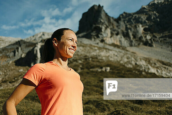 Female explorer smiling while standing against mountain at Cares Trail in Picos De Europe National Park  Asturias  Spain