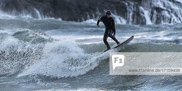 Young man surfing on sea  Broad Haven South Beach  Wales  UK