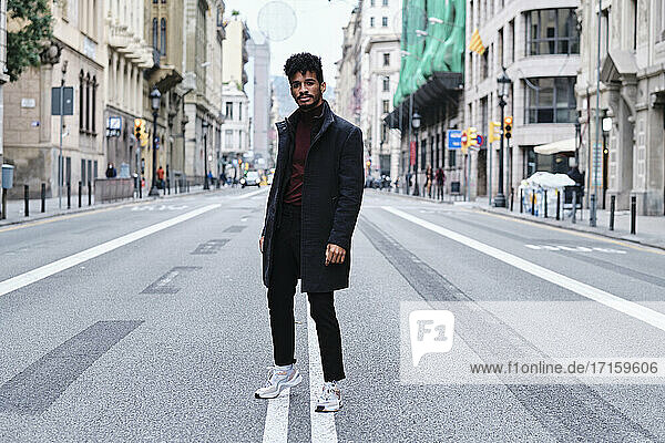 Young fashionable man staring while standing on road in city