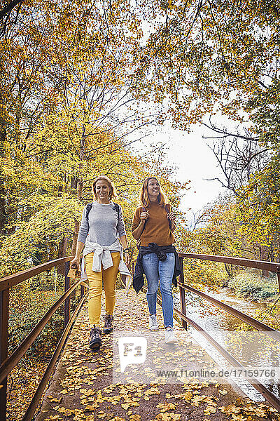 Women smiling while walking on bridge in forest