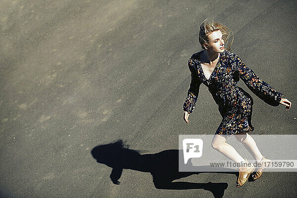 Female fashion model on road while looking away during sunny day