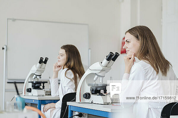 View from the back of young researchers in white coats in a science class