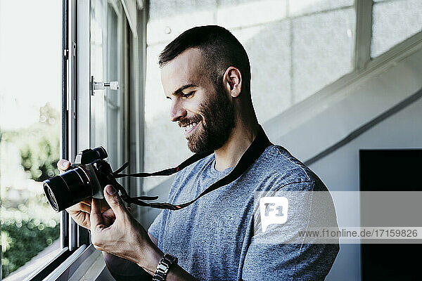 Smiling man working with camera at home