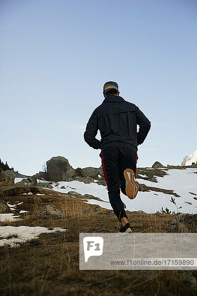 Junger männlicher Sportler beim Joggen auf einem Berg im Winter