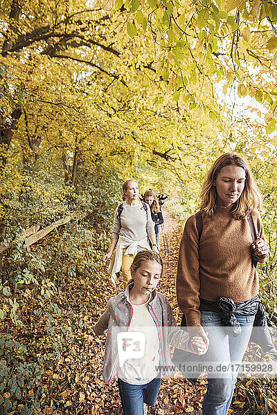 Mature women walking with children while hiking in forest