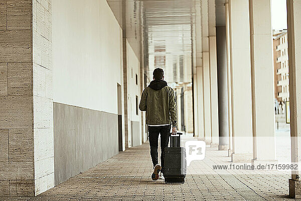 Man pulling suitcase while walking at arcade