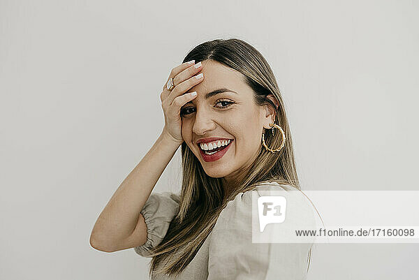 Beautiful woman with head in hand while smiling against white background