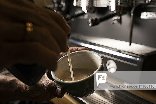 Barista pouring milk while making coffee at cafe