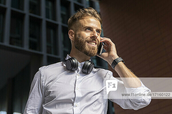 Businessman looking away while talking on mobile phone outdoors