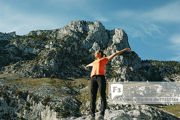 Mid adult woman with arms outstretched standing against mountain at Cares Trail in Picos De Europe National Park  Asturias  Spain