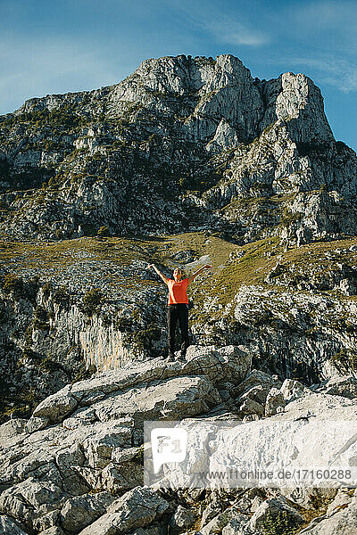 Carefree woman with arms outstretched standing on mountain at Cares Trail in Picos De Europe National Park  Asturias  Spain