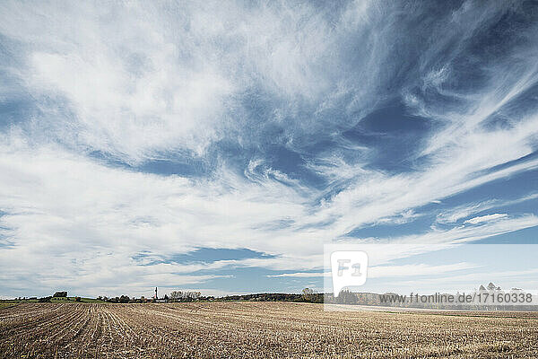 Barren agricultural field against blue sky at countryside