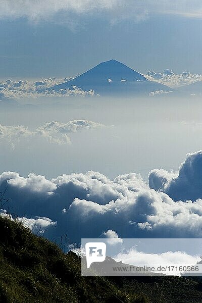 Mount Agung  der höchste Vulkan auf Bali  erhebt sich hoch über den Wolken vom Campingplatz am ersten Tag des dreitägigen Mount Rinjani Treks  Lombok  Indonesien. Ein Großteil der dreitägigen Mount Rinjani-Wanderung wird über den Wolken verbracht. Das Zelten über den Wolken in beiden Nächten ist einer der Höhepunkte  mit einem atemberaubenden Blick auf alle drei Gili-Inseln (Gili Trawangan  Gili Meno und Gili Air)  den 3726 m hohen Gipfel sowie den Mount Agung und Mount Batur auf Bali vom Campingplatz der ersten Nacht.