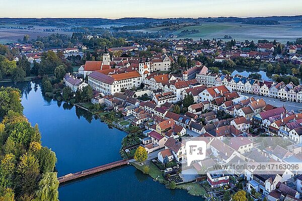 Aerial view before sunrise of the Telc Castle with foreground bridge  pond and rolling hills in the Czech Republic.