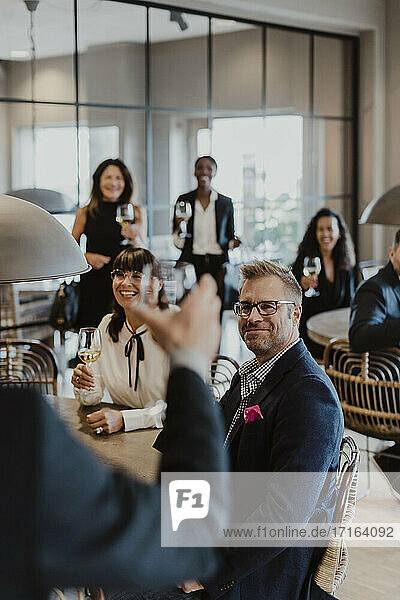 Smiling male and female toasting wineglasses in party at office