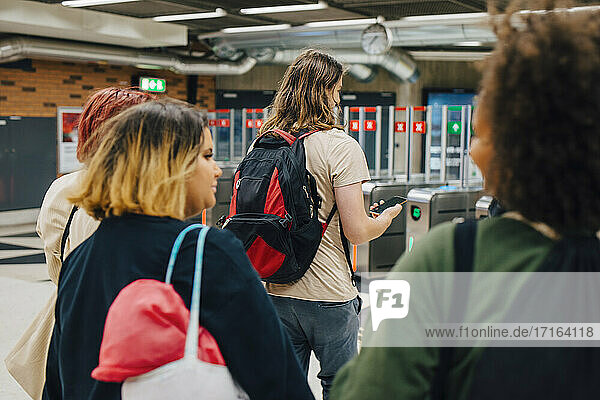 Rear view of university students walking at subway station