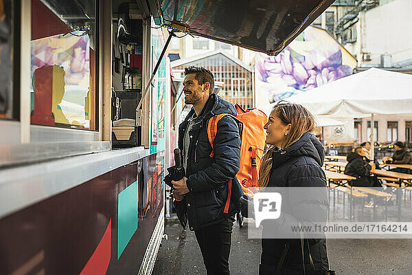 Happy couple standing by counter at food truck