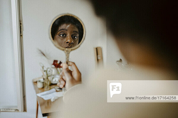 Junge Frau schaut in den Spiegel zu Hause