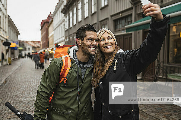 Lächelndes heterosexuelles Paar nimmt Selfie auf der Straße in der Stadt