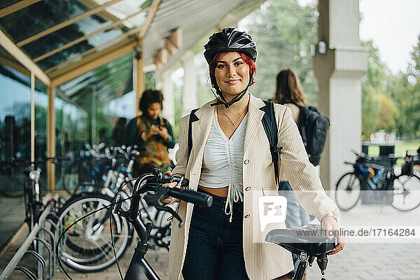 Porträt einer Studentin mit Fahrrad auf dem Universitätscampus