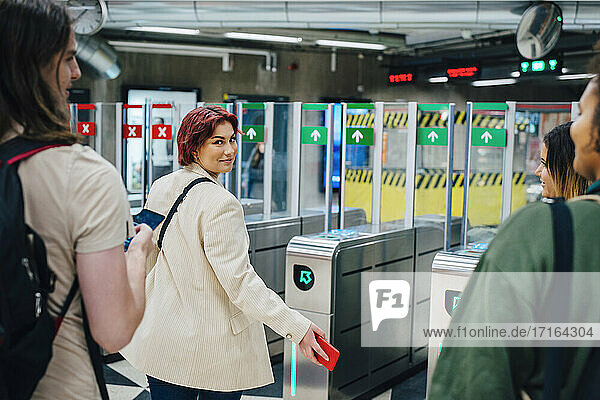 Porträt einer jungen Studentin  die in einer U-Bahn-Station über die Schulter schaut
