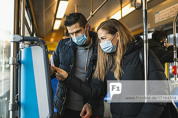 Kaukasisches Paar kauft Fahrkarte in Straßenbahn während COVID-19