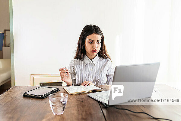 Junge Frau arbeitet zu Hause am Laptop