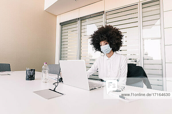 Geschäftsfrau mit Gesichtsmaske bei der Arbeit
