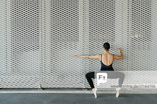 Female dancer practicing ballet dance in front of metal wall