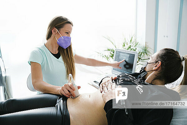 Female nurse doing ultrasound scan on patient while pointing at monitor