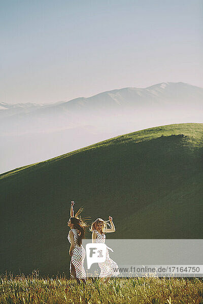 Lesbian couple dancing against mountain