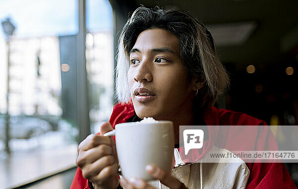 Young man having coffee in cafe during winter