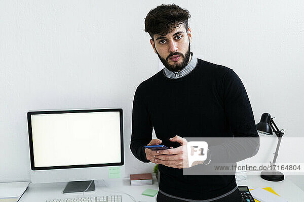 Portrait of businessman holding smart phone in office