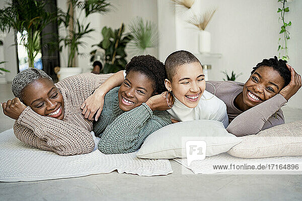 Happy female friends enjoying while lying down in living room