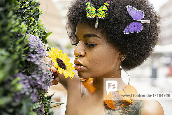 Young Afro woman smelling flower outdoors