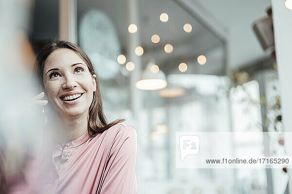 Geschäftsfrau lächelt  während sie in einem Café mit ihrem Smartphone telefoniert